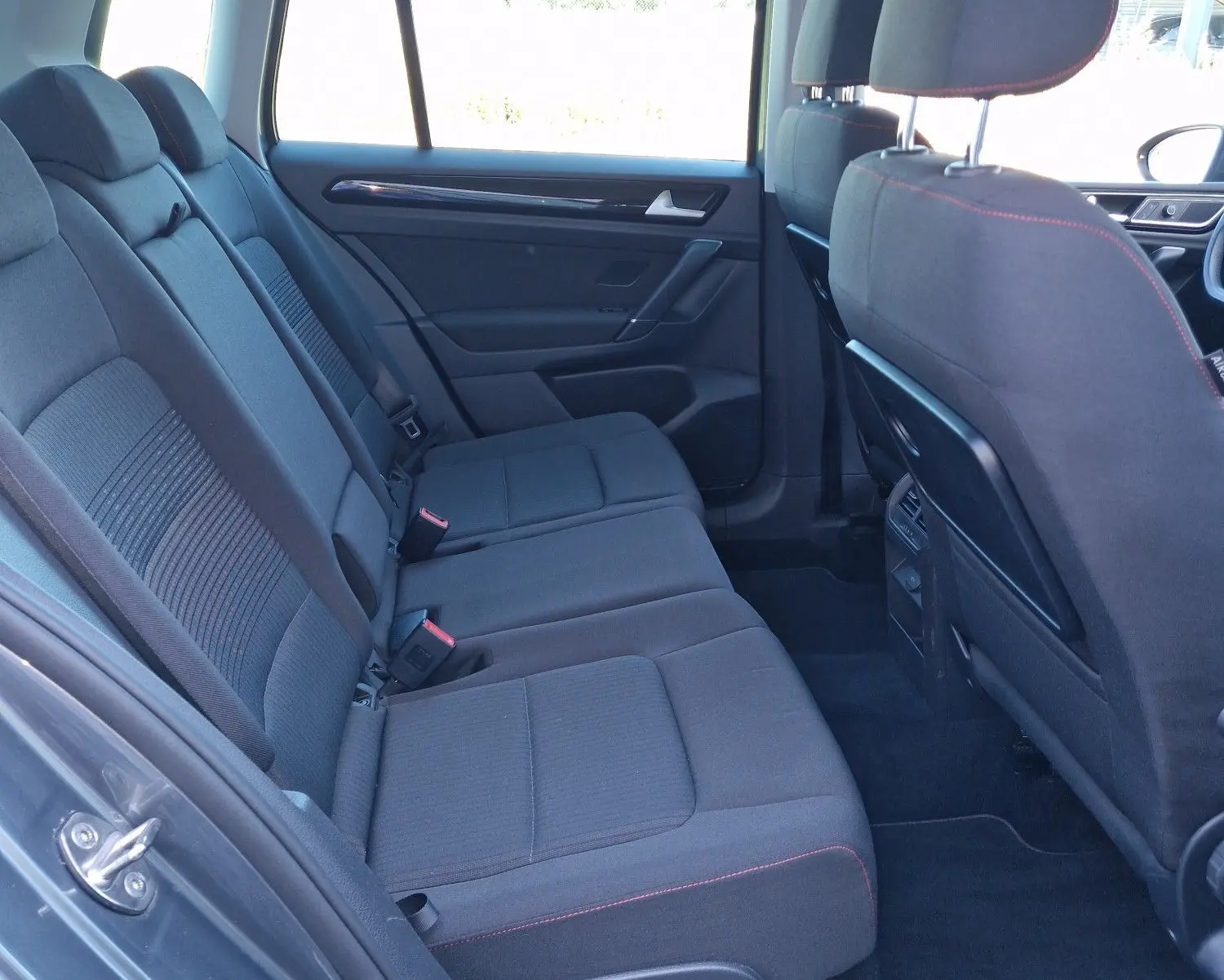 Vue intérieure côté gauche des sièges arrière gris foncé avec surpiqûres rouges du Volkswagen Golf Sportsvan 2017 gris Indium Metal.