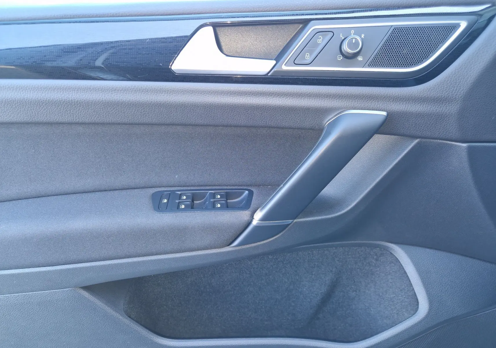 Vue rapprochée de la porte avant gauche de la Volkswagen Golf Sportsvan gris Indium, avec commandes de vitres et rétroviseurs.