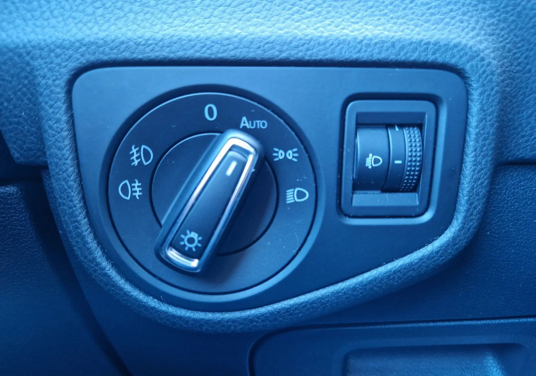 Gros plan sur le bouton de commande des phares et le réglage d’intensité lumineuse dans l’habitacle d’une Volkswagen Golf Sportsvan gris Indium.