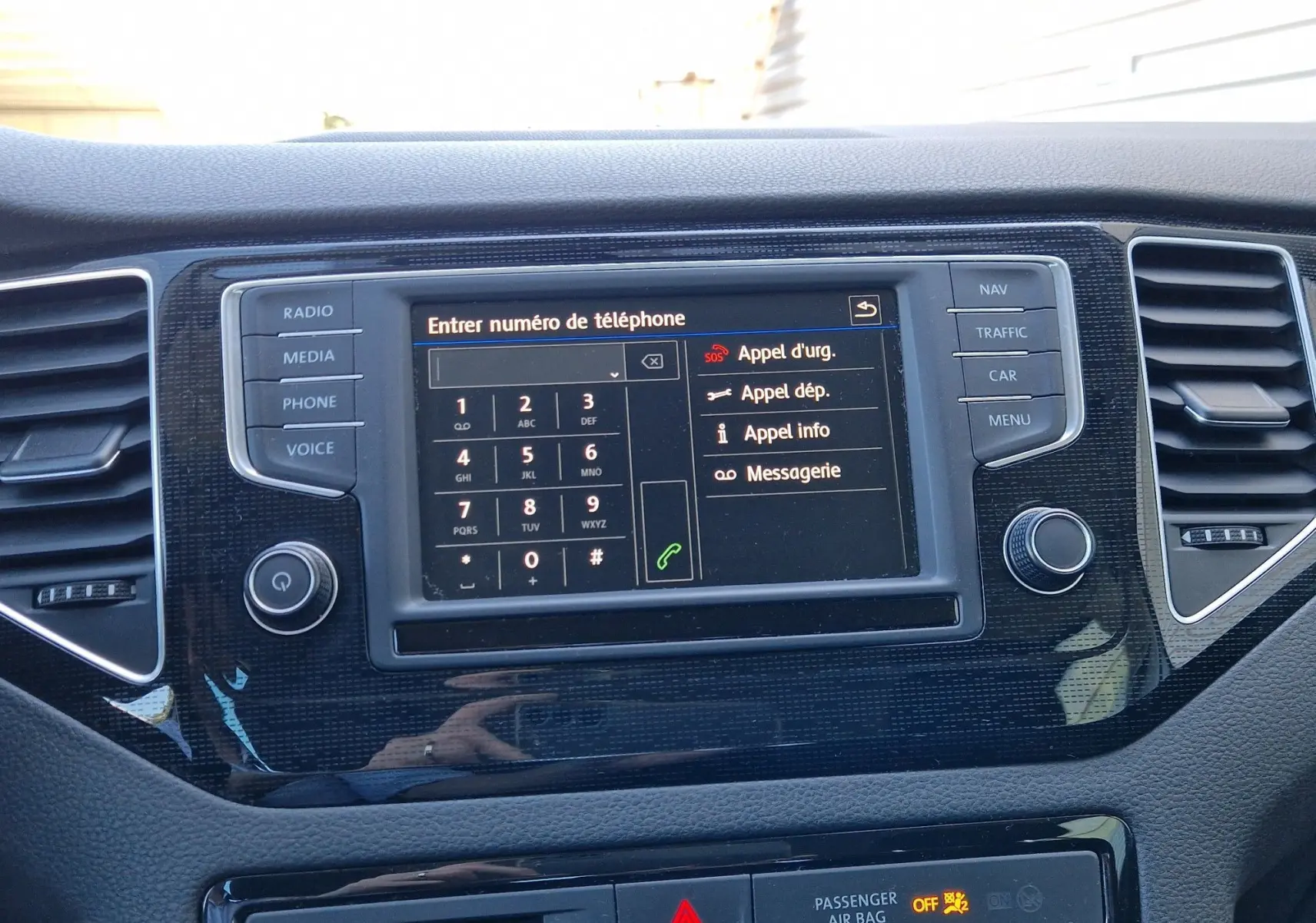 Vue rapprochée de la console centrale de la Volkswagen Golf Sportsvan 2017, écran tactile affichant le menu téléphone, entouré de boutons noirs.