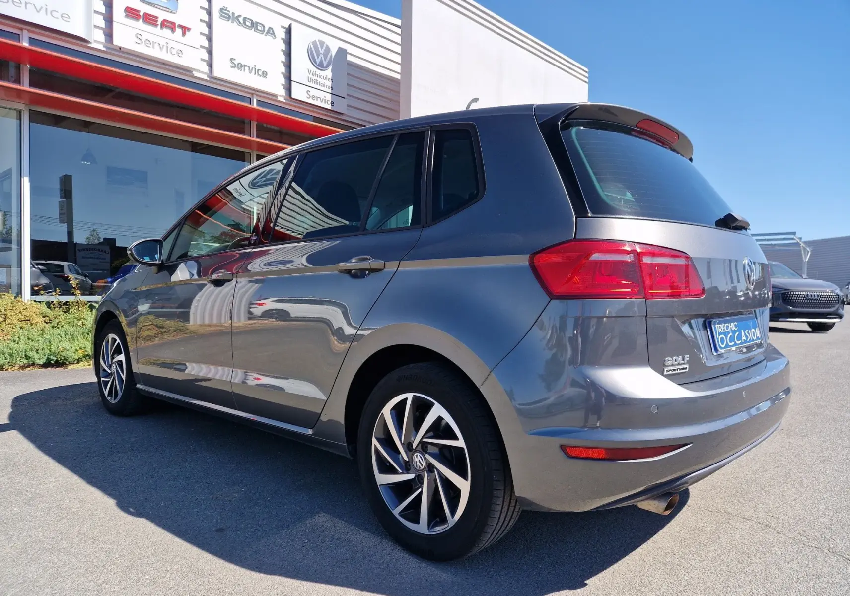 Vue 3/4 arrière droite d'une Volkswagen Golf Sportsvan gris Indium métallisé, avec jantes alliage et feux arrière LED.