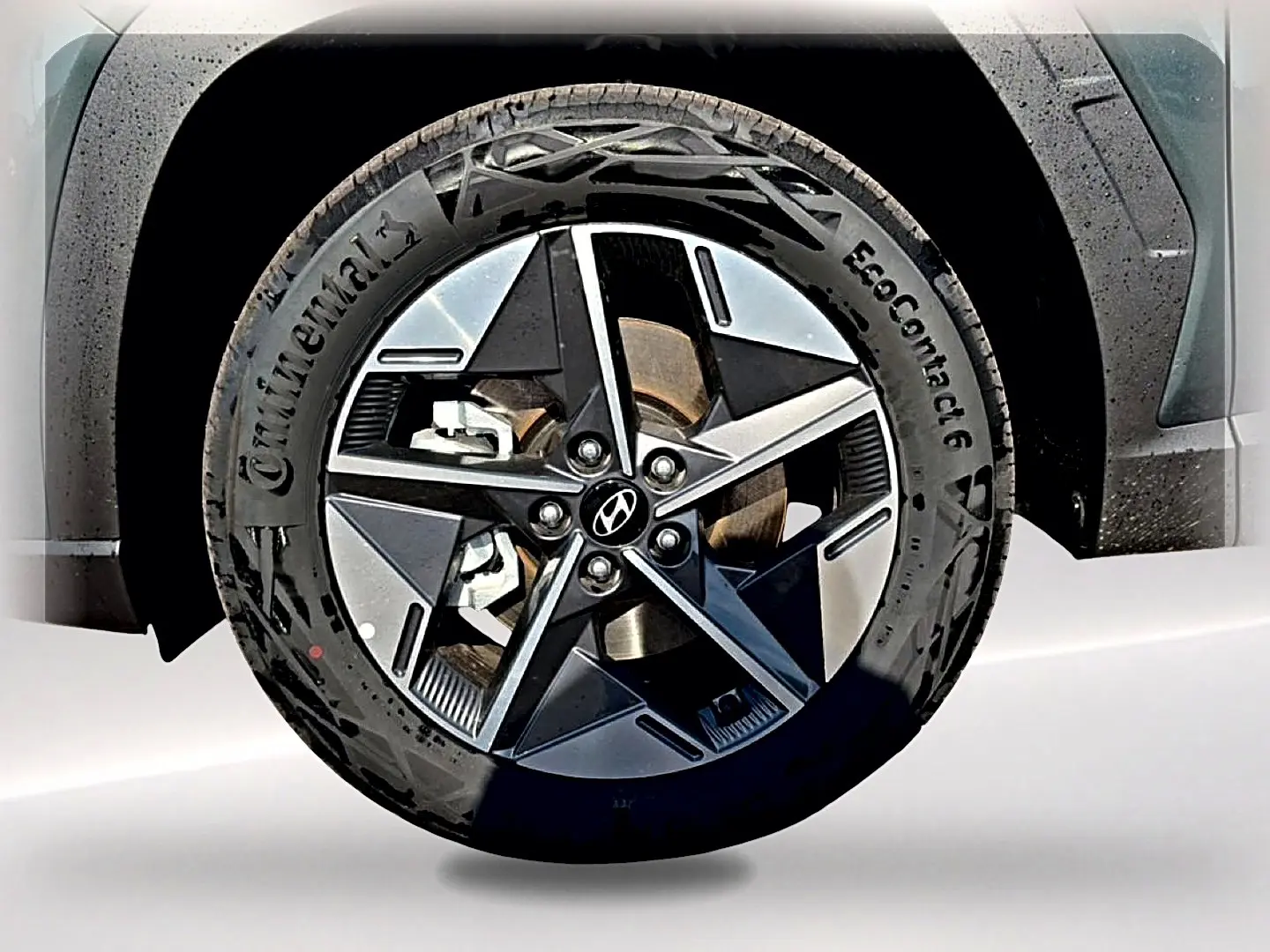 Gros plan sur la jante alu 18 pouces noire et grise d’un Hyundai Tucson vert, avec logo Hyundai au centre.