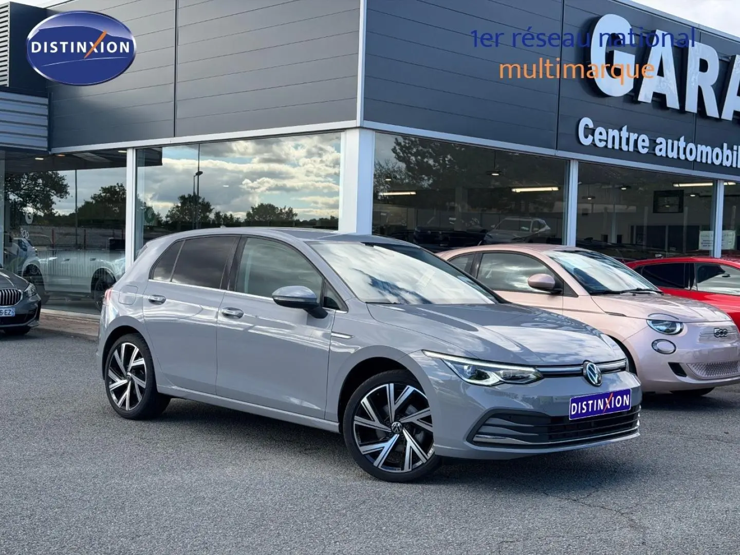 Volkswagen Golf 1.5 TSI gris lunaire en 3/4 avant droit, avec jantes alliage et phares LED allumés.