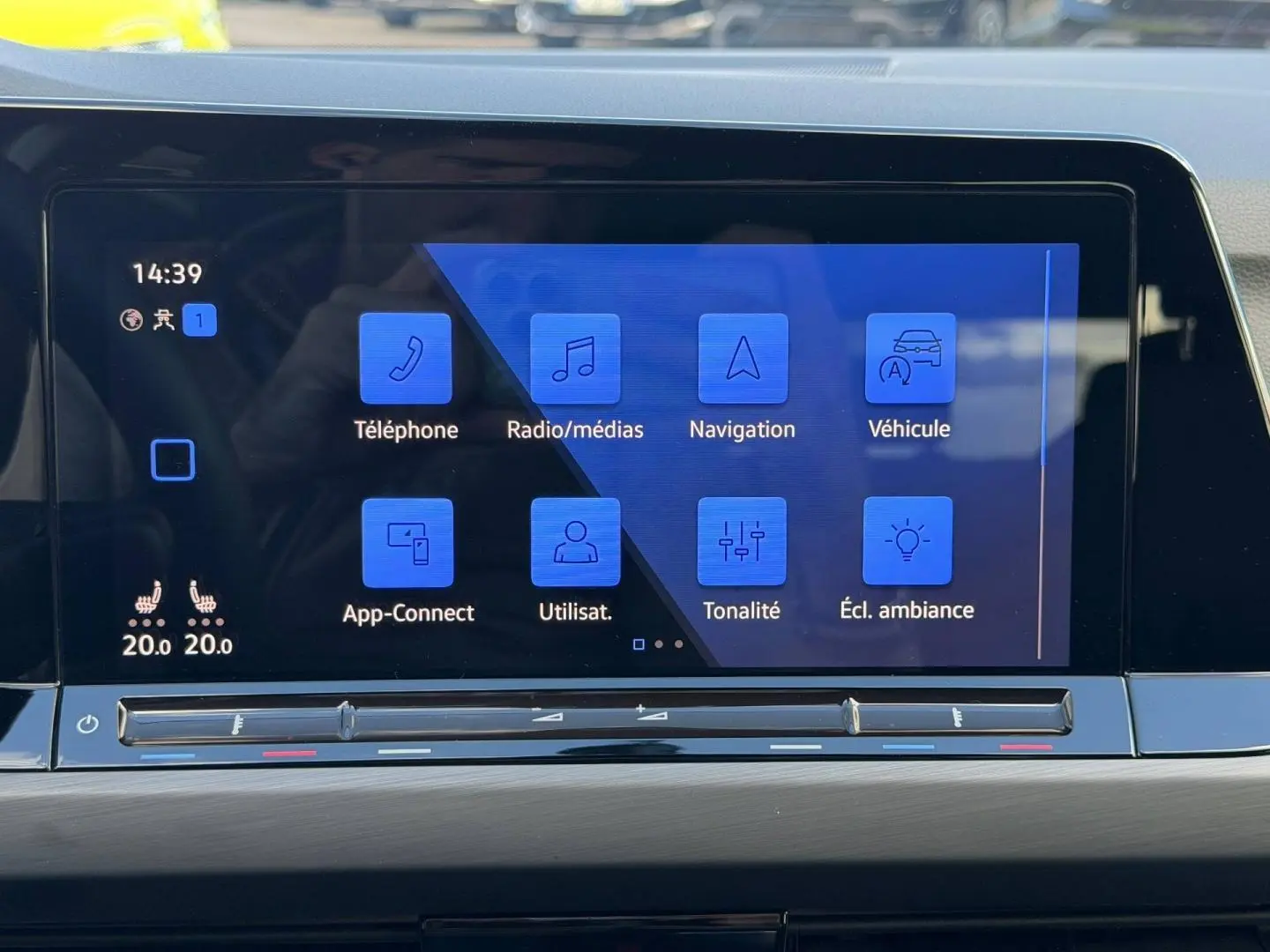 Écran tactile central de la Volkswagen Golf 2024 affichant les options de navigation et radio, avec commandes climatisation en dessous.