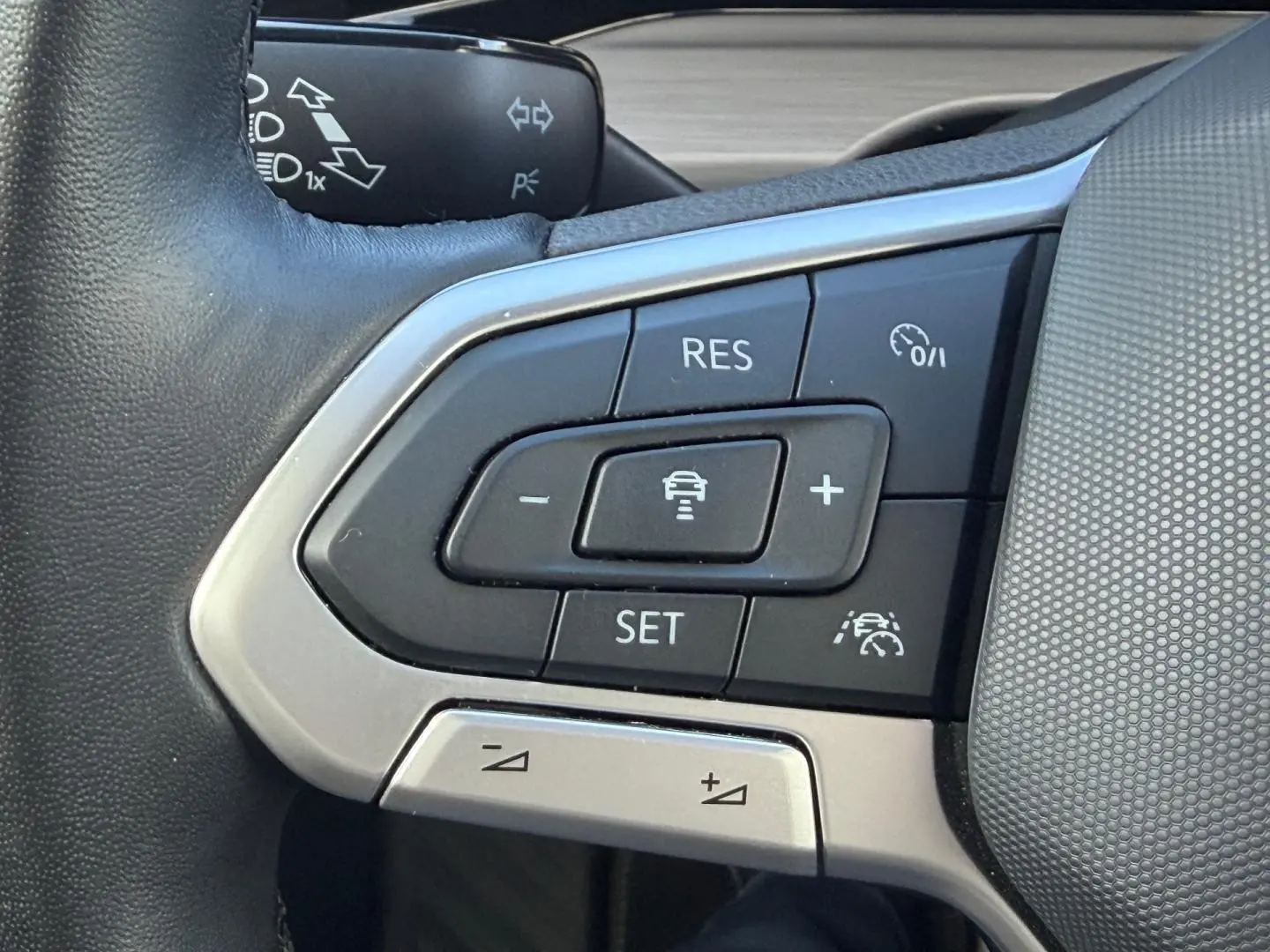 Gros plan sur les commandes du volant cuir noir de la Volkswagen Golf 2024, boutons de régulateur de vitesse et assistance.