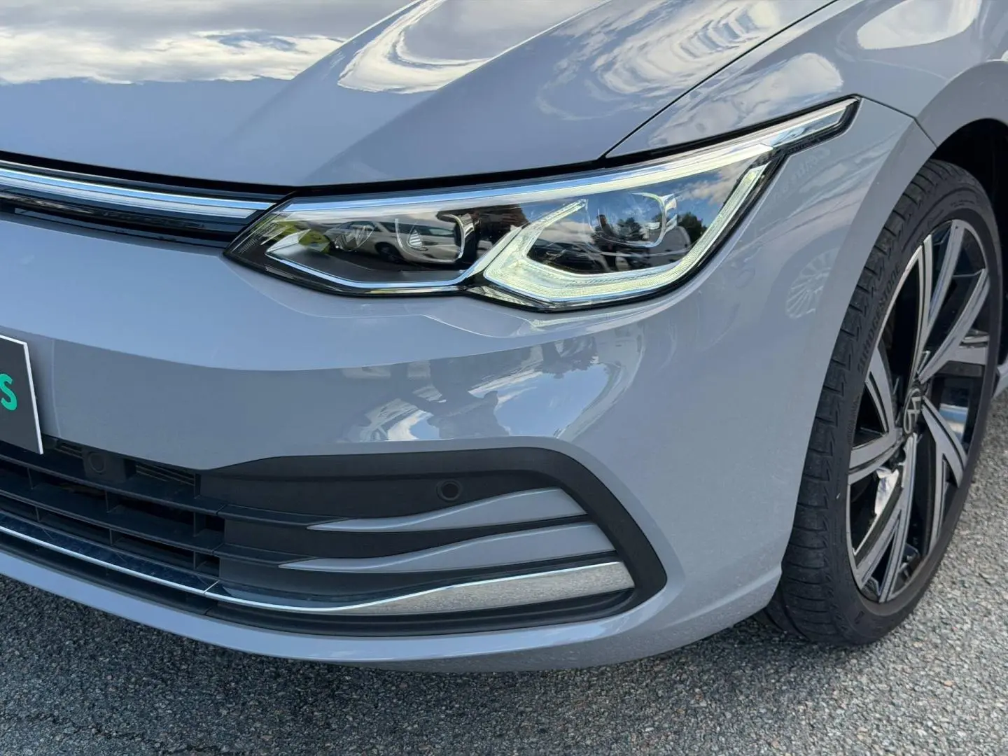 Gros plan sur l'avant droit gris lunaire de la Volkswagen Golf 2024, mettant en valeur le phare LED et la jante alu.