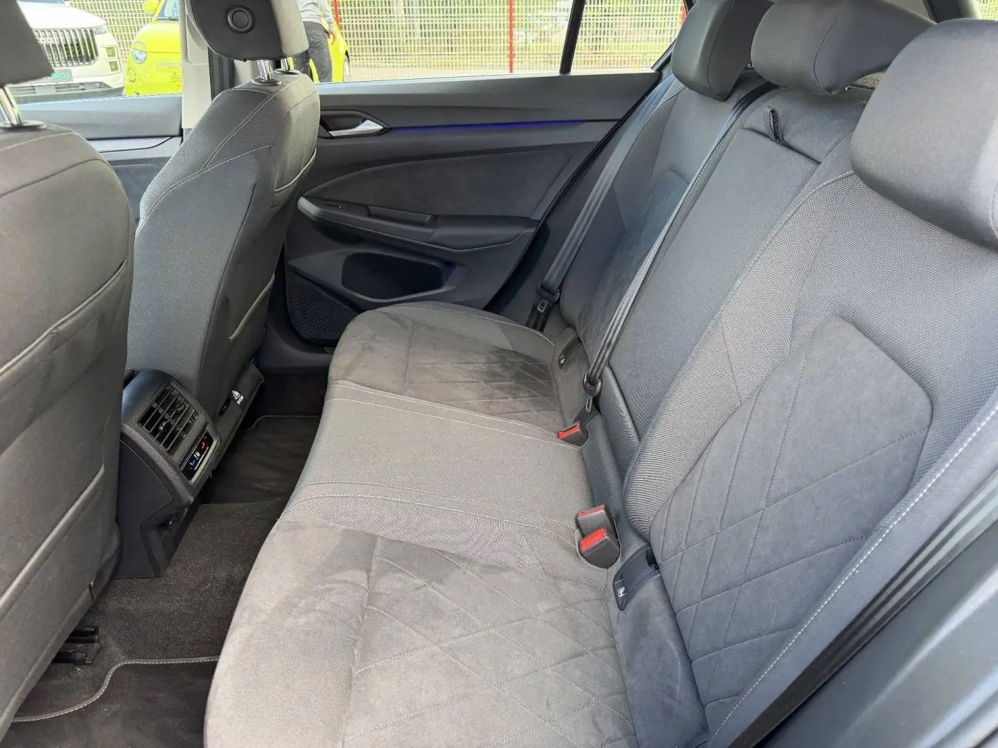 Vue intérieure de la banquette arrière grise de la Volkswagen Golf 1.5 TSI 2024 avec accoudoir central et aérations arrière.