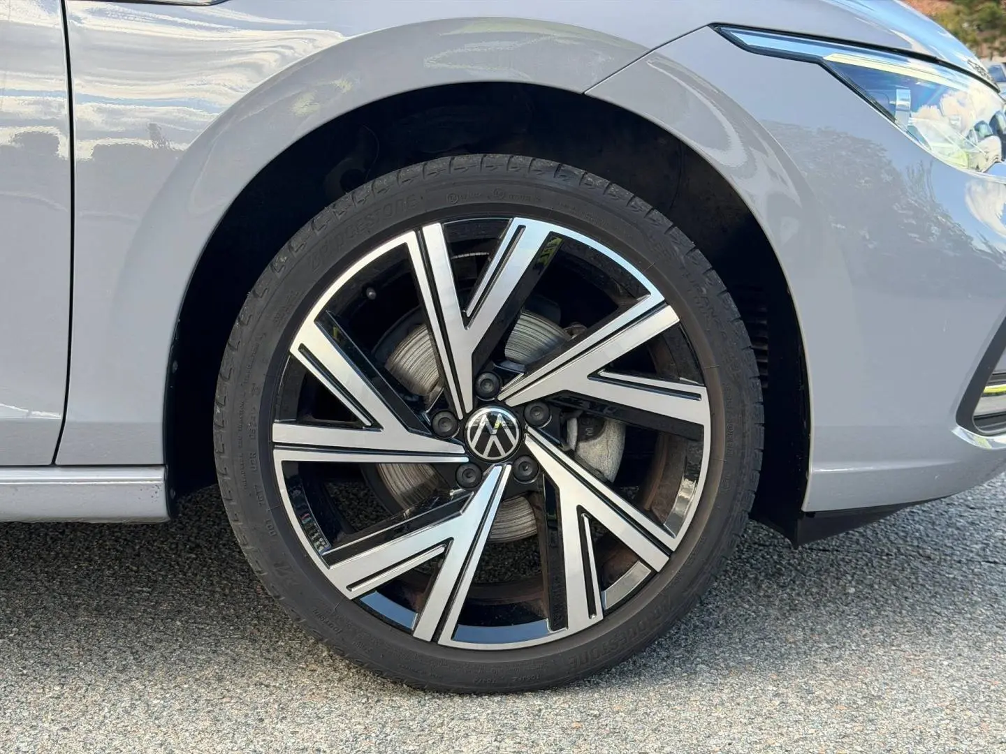 Gros plan sur la roue avant droite d'une Volkswagen Golf gris lunaire avec jante alliage au design moderne.