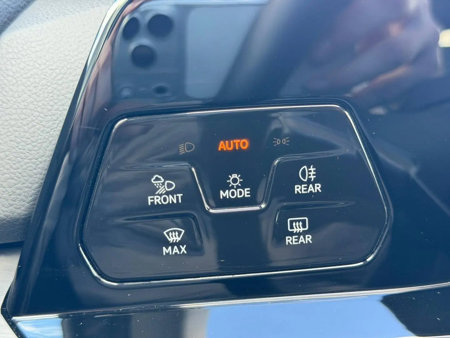 Gros plan sur les commandes d’éclairage et désembuage en plastique noir brillant dans l’habitacle d’une Volkswagen Golf gris lunaire.