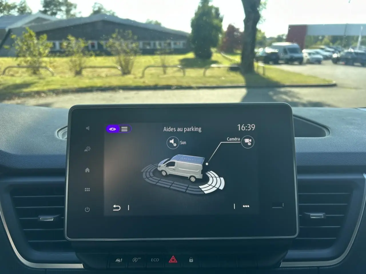 Écran central du Renault Trafic Fourgon gris urbain montrant l'aide au parking avec caméra de recul active.