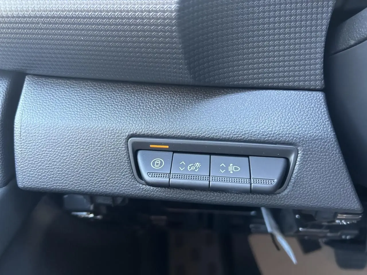 Boutons de réglage d'éclairage et verrouillage sur tableau de bord noir du Renault Trafic Fourgon Gris Urbain, vue intérieure rapprochée.