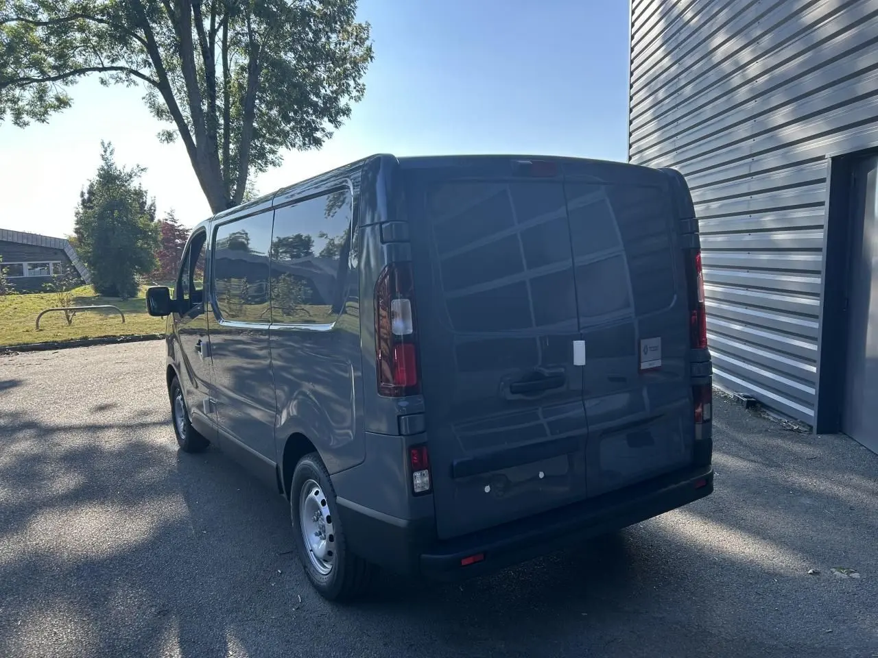 Vue 3/4 arrière droite d'un Renault Trafic Fourgon gris urbain avec portes arrière fermées et jantes acier.