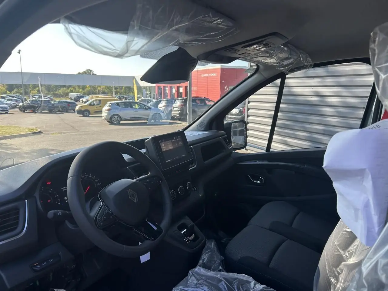 Intérieur du Renault Trafic Fourgon 2025 vu côté conducteur, avec tableau de bord moderne et sièges noirs.