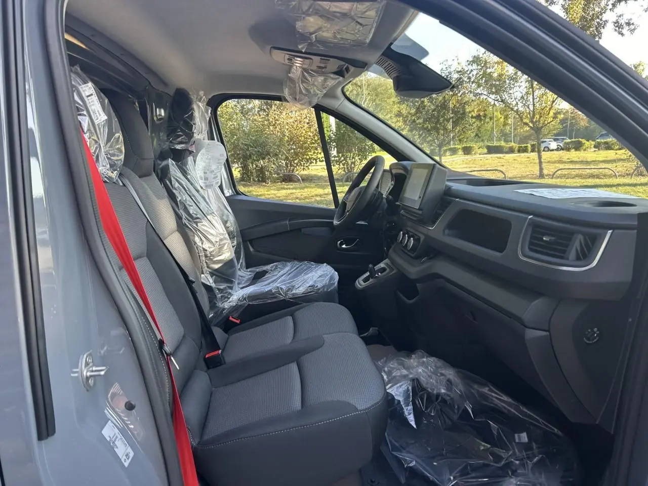 Intérieur côté conducteur du Renault Trafic Fourgon gris urbain 2025, avec sièges protégés et tableau de bord moderne.