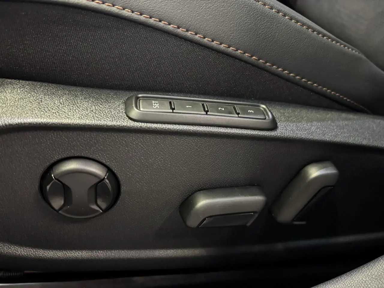 Détail des commandes de réglage électrique du siège conducteur noir avec surpiqûres cuivrées dans une CUPRA Leon 2026.