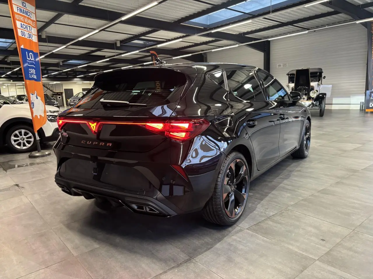 Vue 3/4 arrière droite de la CUPRA Leon noir midnight avec feux arrière Tri-LED et jantes alliage 18'' cuivrées.