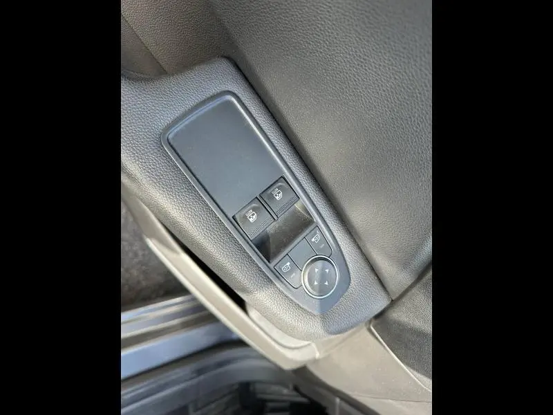 Gros plan sur les commandes de réglage des rétroviseurs et des vitres côté conducteur d'une Renault Clio gris 2023.