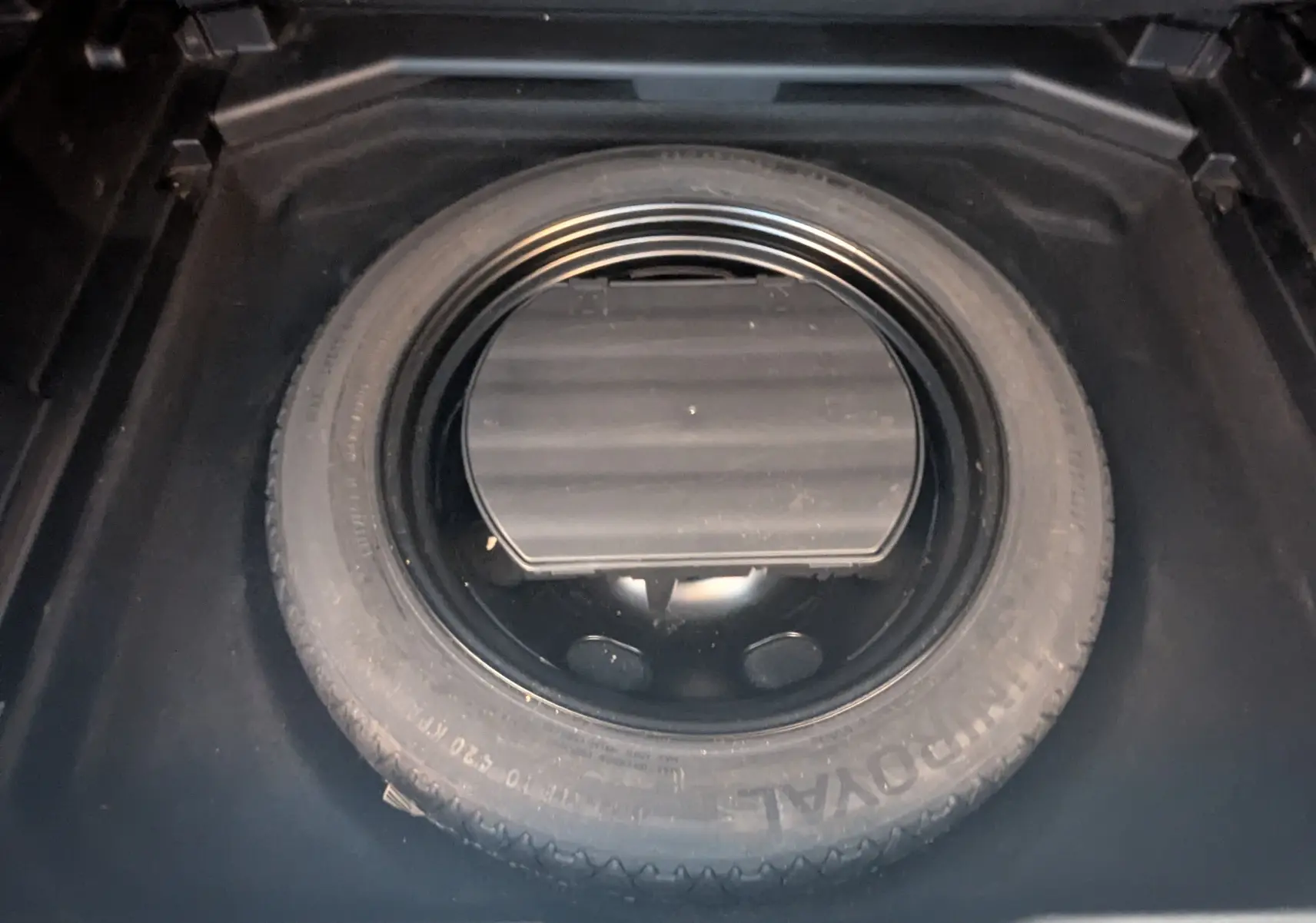 Vue rapprochée de la roue de secours noire dans le coffre d'un Peugeot 3008 blanc toit noir HDi 130 Allure 2018.