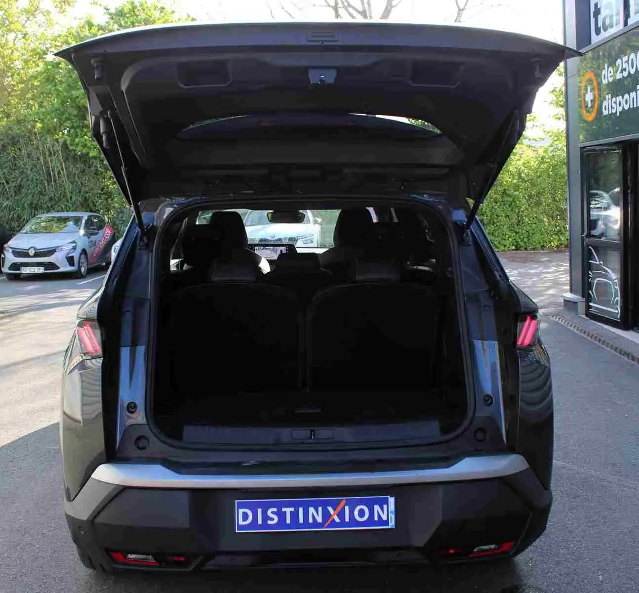 Vue arrière d'un Peugeot 5008 gris titane métallisé 2025 avec hayon ouvert, montrant l'espace de coffre.