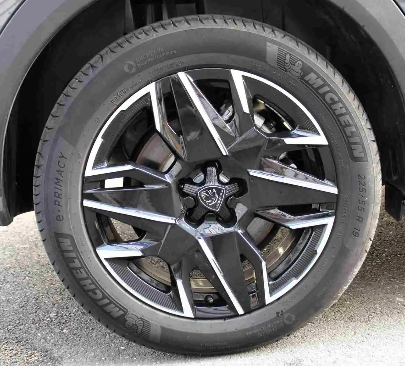 Gros plan sur la jante alliage noire et argentée du Peugeot 5008 III Hybrid gris titane, avec pneu Michelin 225/55 R19.