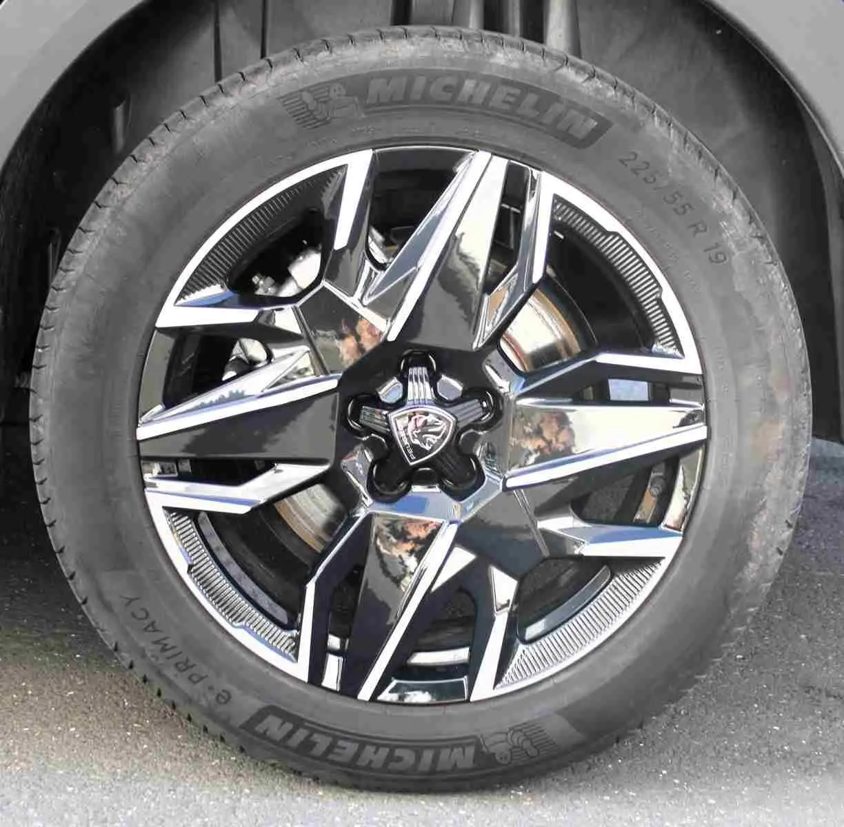 Gros plan sur la jante alliage noire et argentée avec logo Peugeot, montée sur pneu Michelin d’un Peugeot 5008 gris titane.