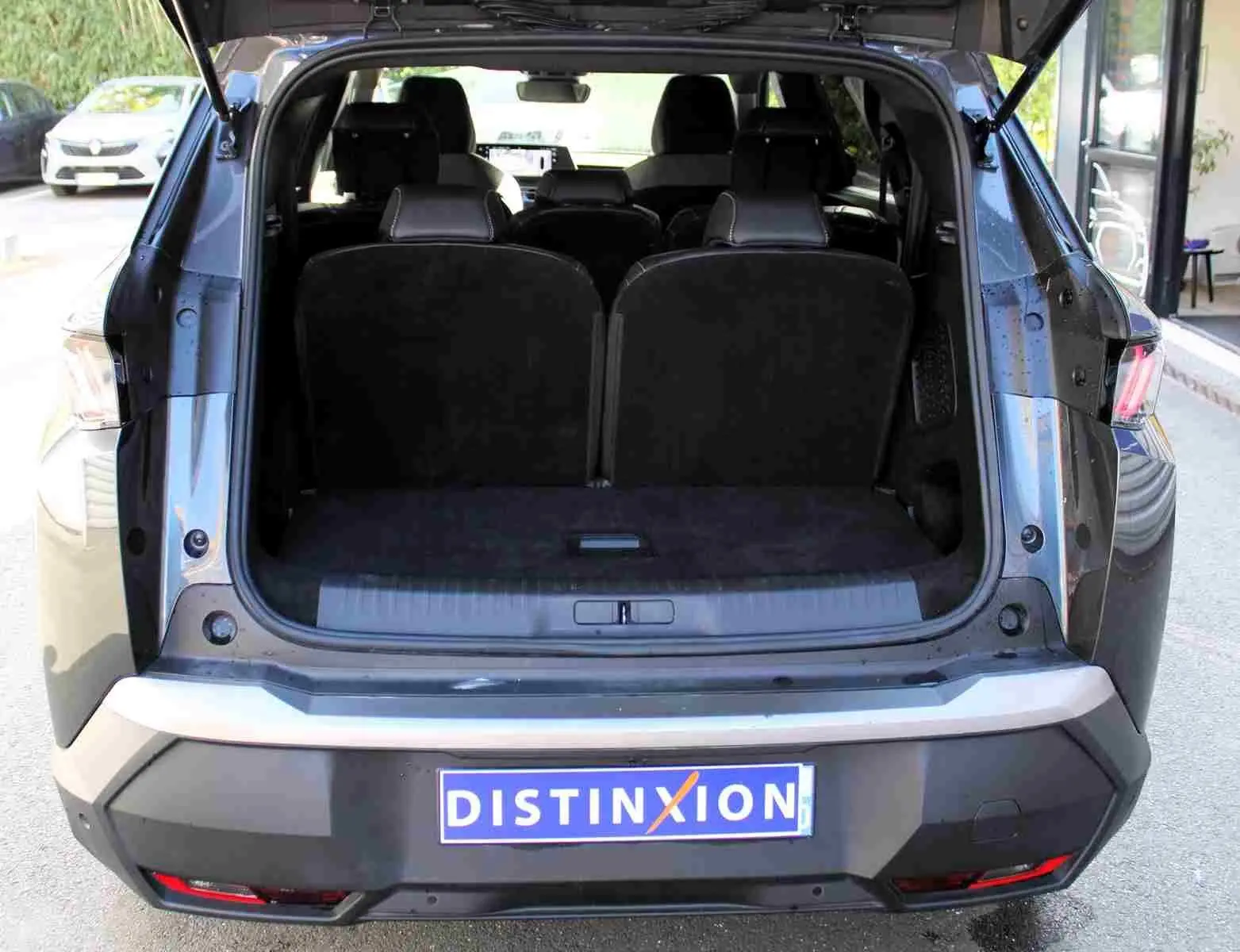 Vue arrière du Peugeot 5008 gris titane métal 2025 avec coffre ouvert et sièges arrière visibles.