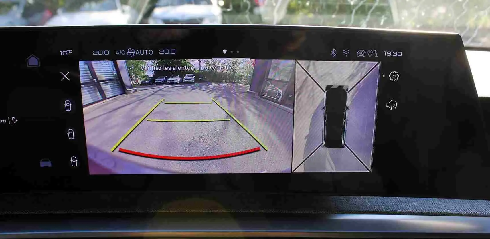 Écran multimédia du Peugeot 5008 Hybrid montrant la caméra de recul avec vue arrière et top-down en extérieur.