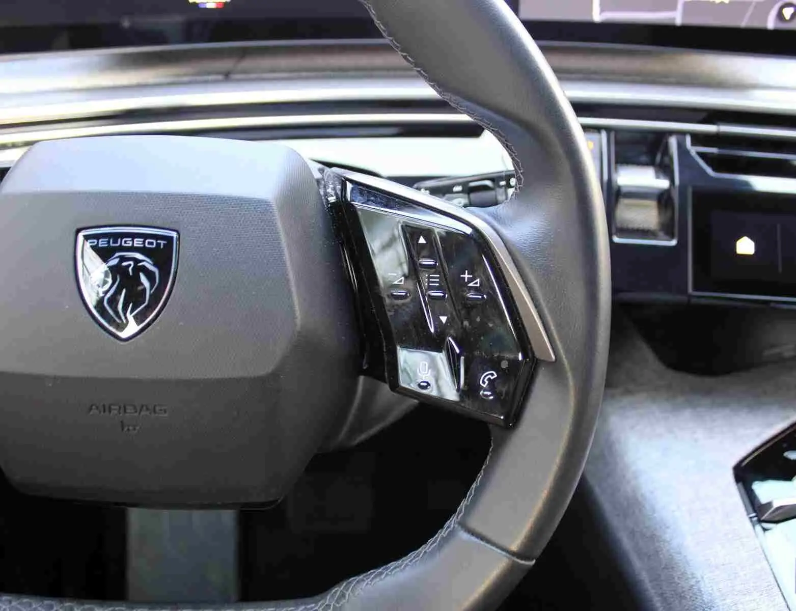 Gros plan sur le volant cuir noir du Peugeot 5008 2025 avec commandes intégrées et logo lion au centre.