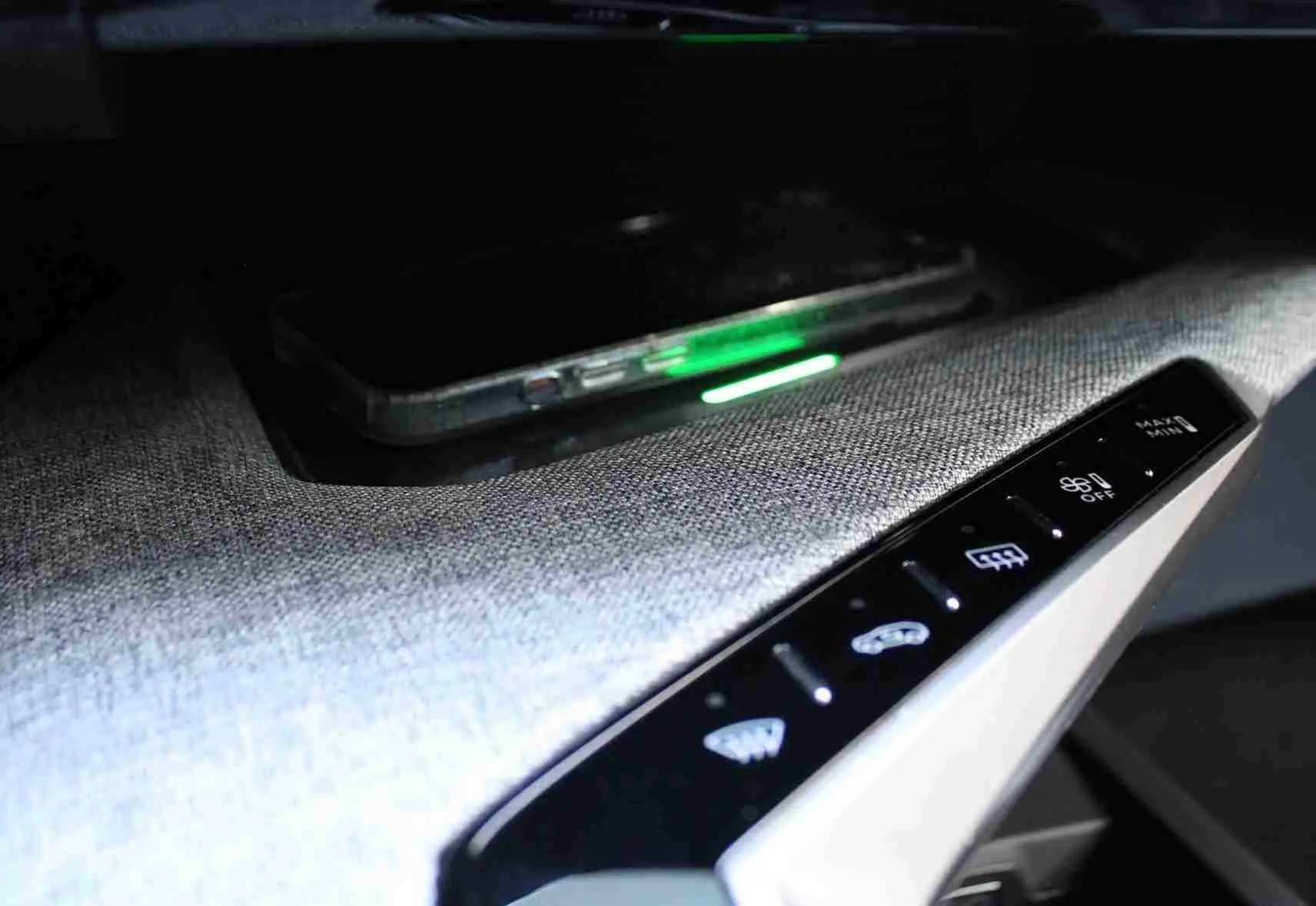 Détail du tableau de bord du Peugeot 5008 III Hybrid 2025 avec console en tissu gris et commandes tactiles éclairées.