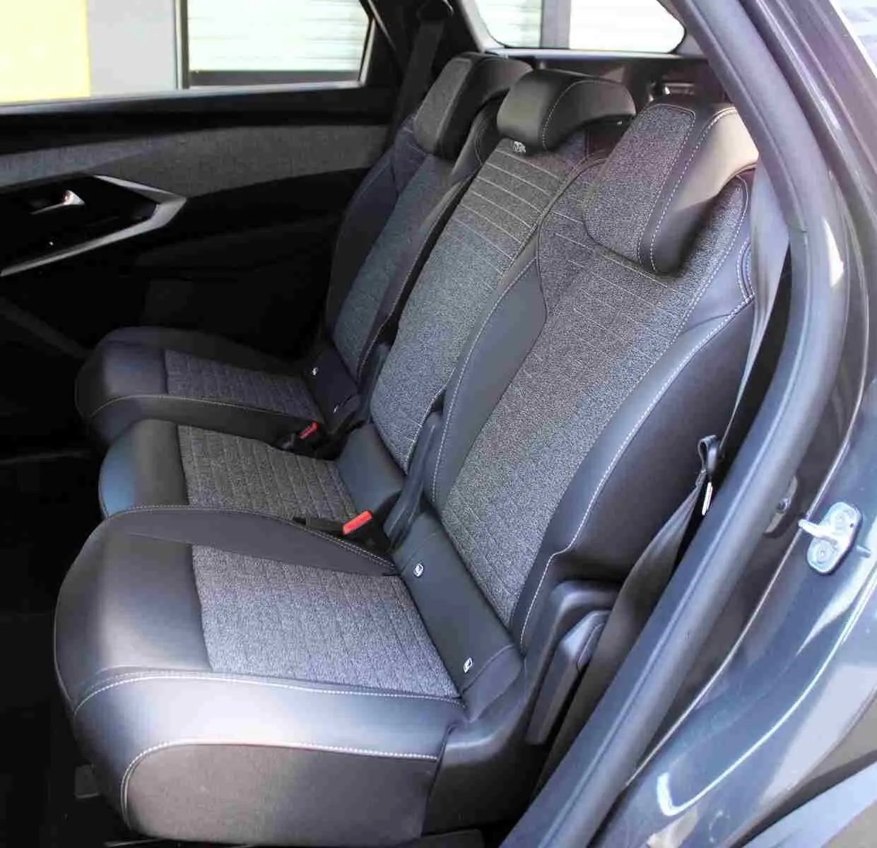 Vue latérale des sièges arrière en tissu gris et cuir noir du Peugeot 5008 gris titane, avec ceinture et appuie-têtes visibles.