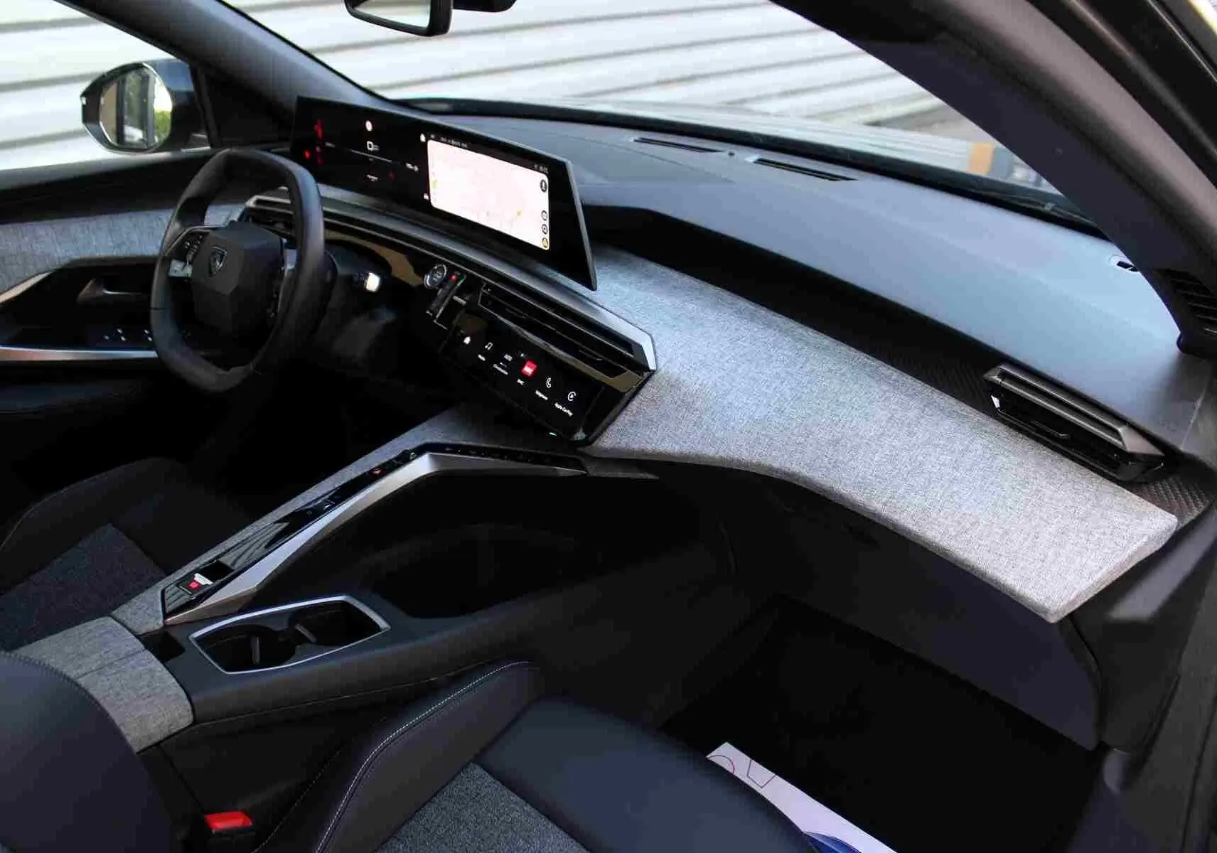 Vue intérieure côté conducteur du Peugeot 5008 2025, tableau de bord gris clair avec écran tactile panoramique.