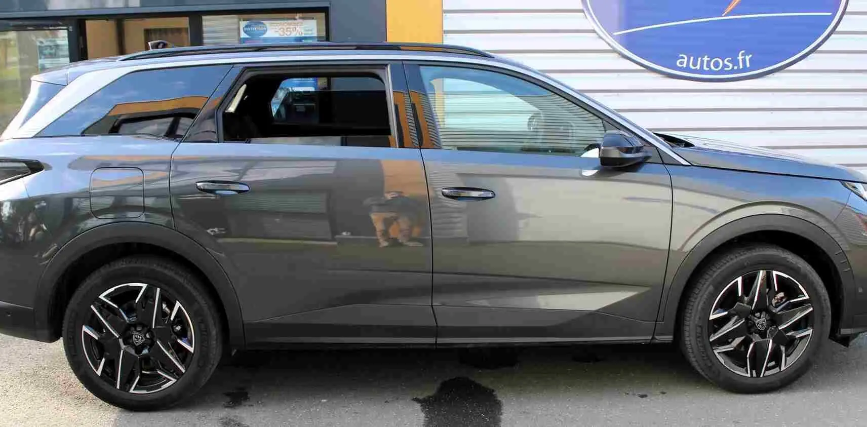 Profil droit du Peugeot 5008 gris titane métal 2025 avec jantes noires et toit ouvrant panoramique.