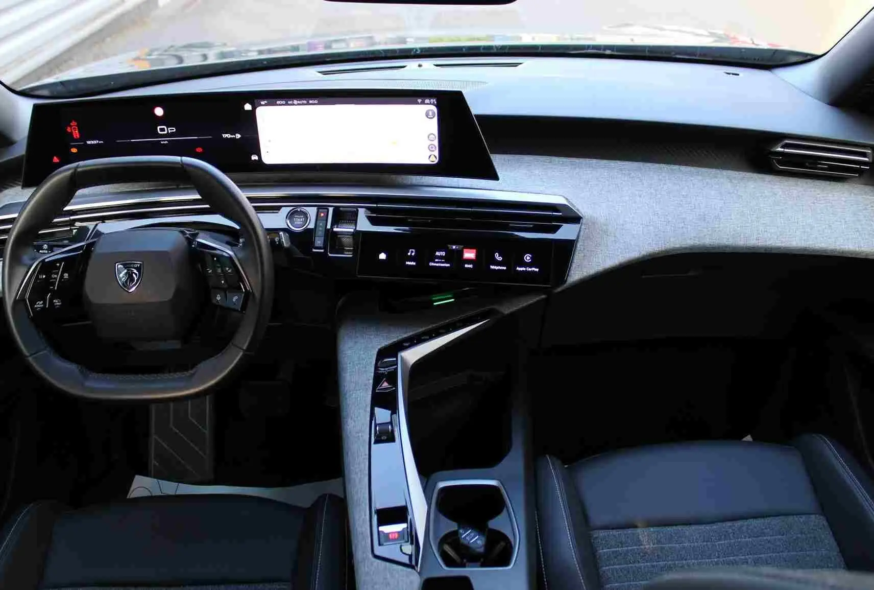 Vue intérieure du tableau de bord et volant du Peugeot 5008 hybride 2025 avec finition gris noir et écran tactile large.