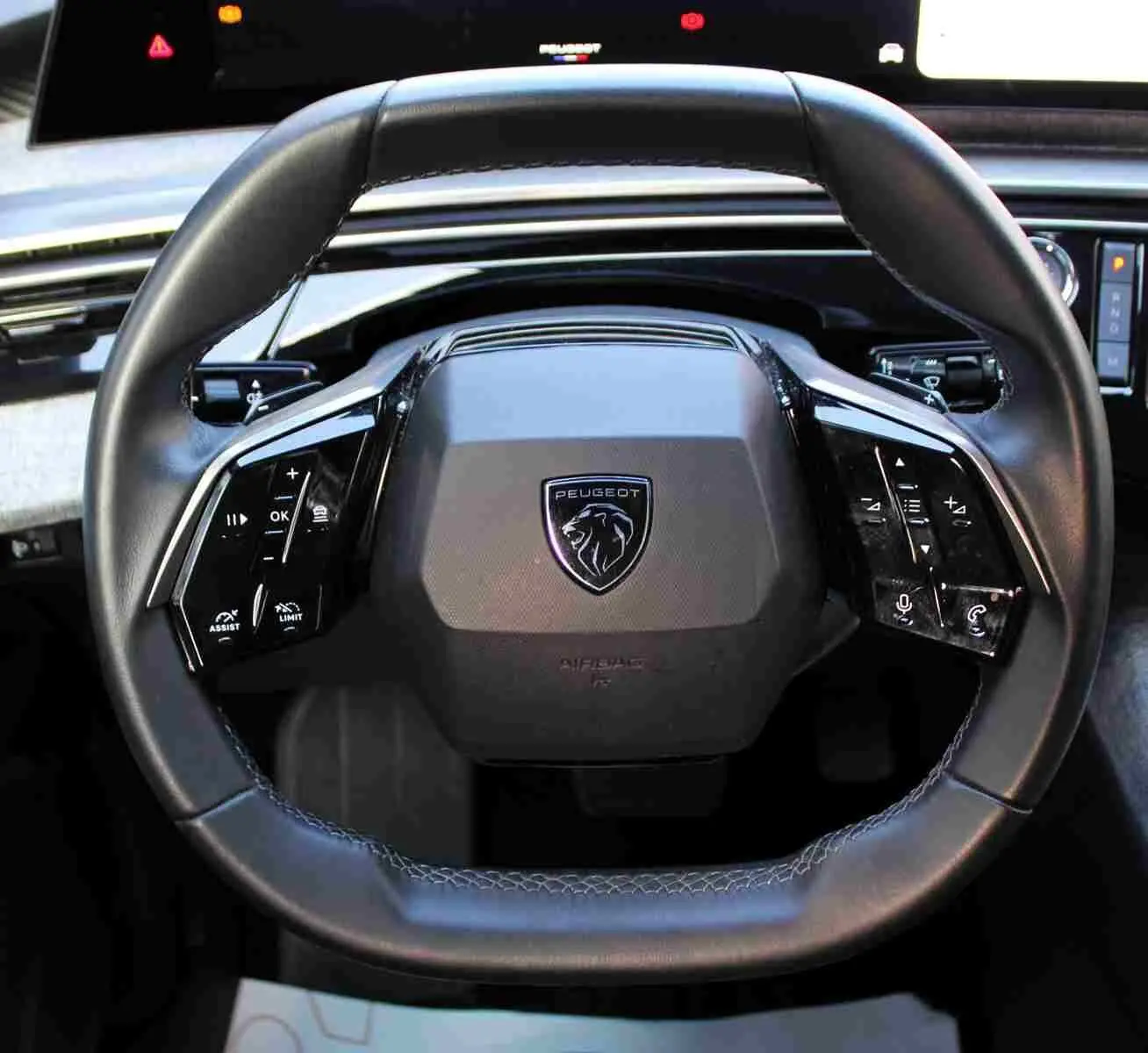 Vue rapprochée du volant cuir noir du Peugeot 5008 2025, avec commandes intégrées et logo lion central.