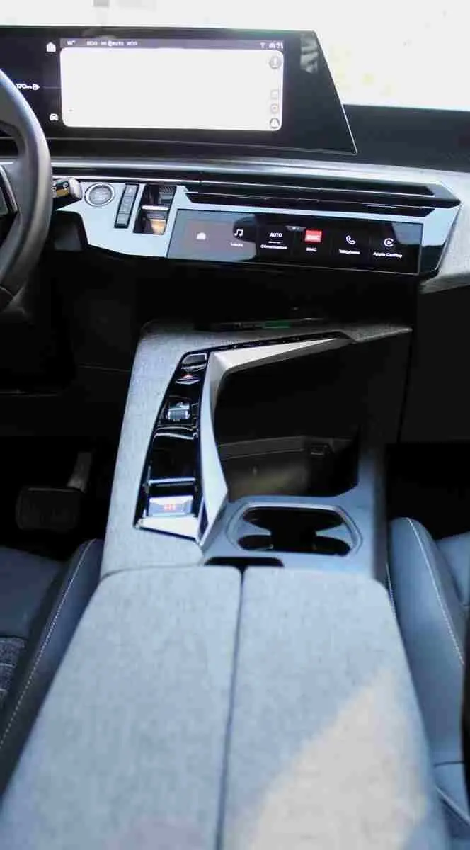 Vue intérieure rapprochée de la console centrale et du tableau de bord numérique du Peugeot 5008 Hybrid 2025, finition tissu gris noir.