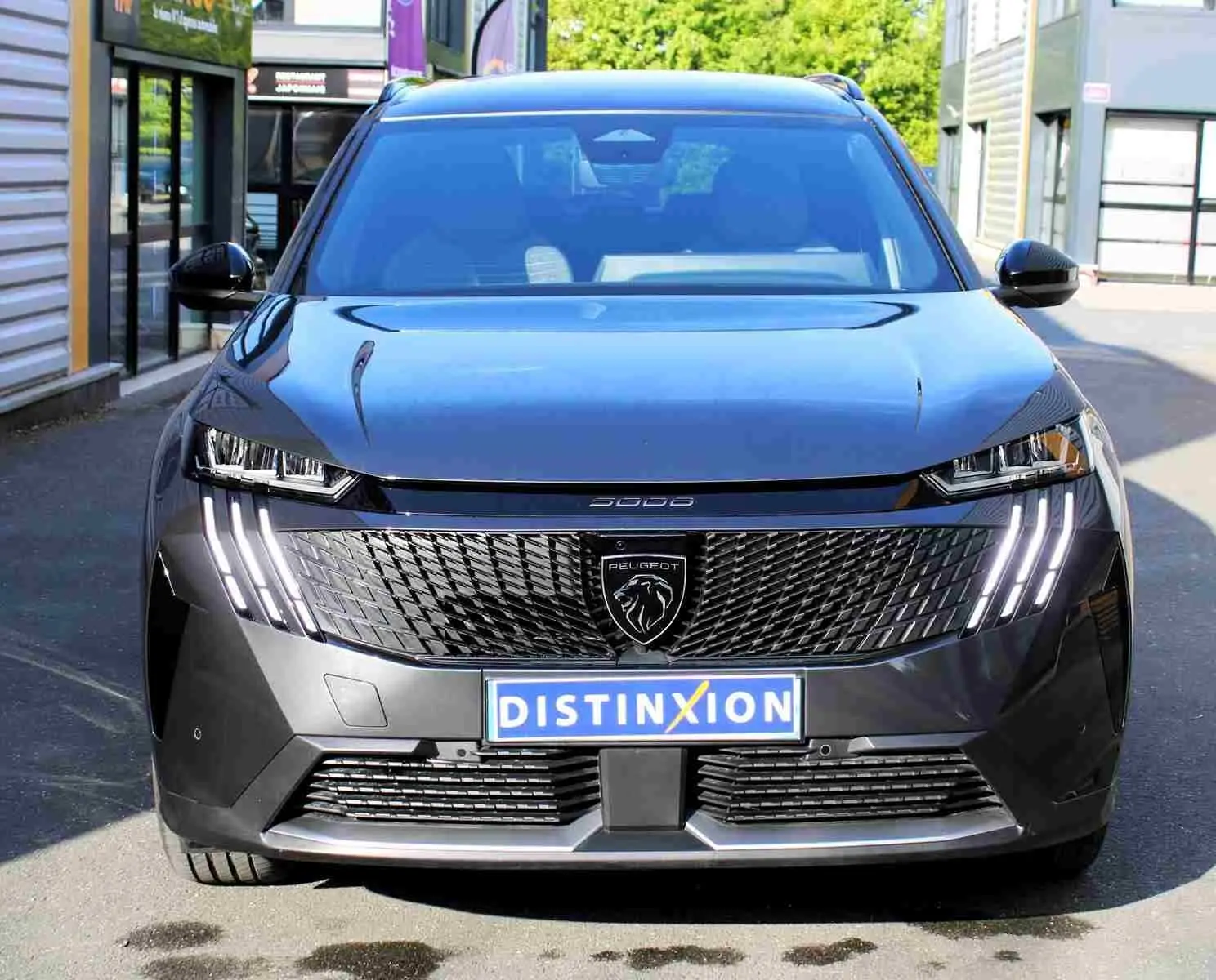Vue de face du Peugeot 5008 gris titane métal 2025 avec calandre noire et feux LED verticaux allumés.