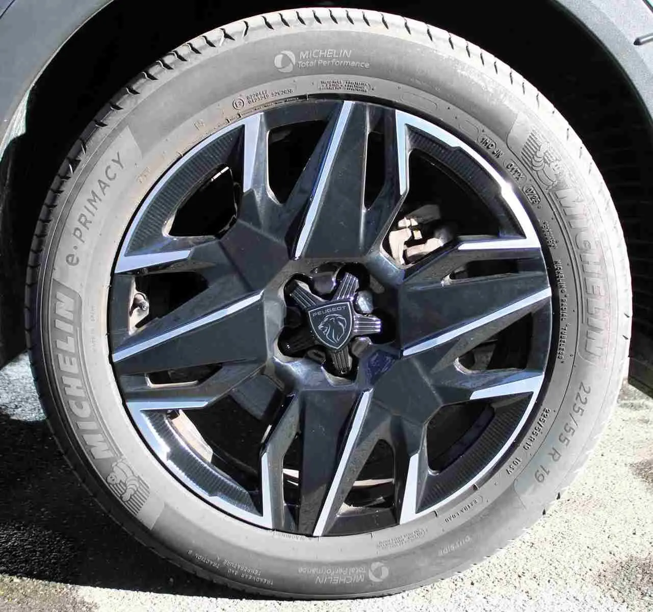 Gros plan sur la jante alliage noire et argentée du Peugeot 5008 gris titane, avec logo lion au centre.