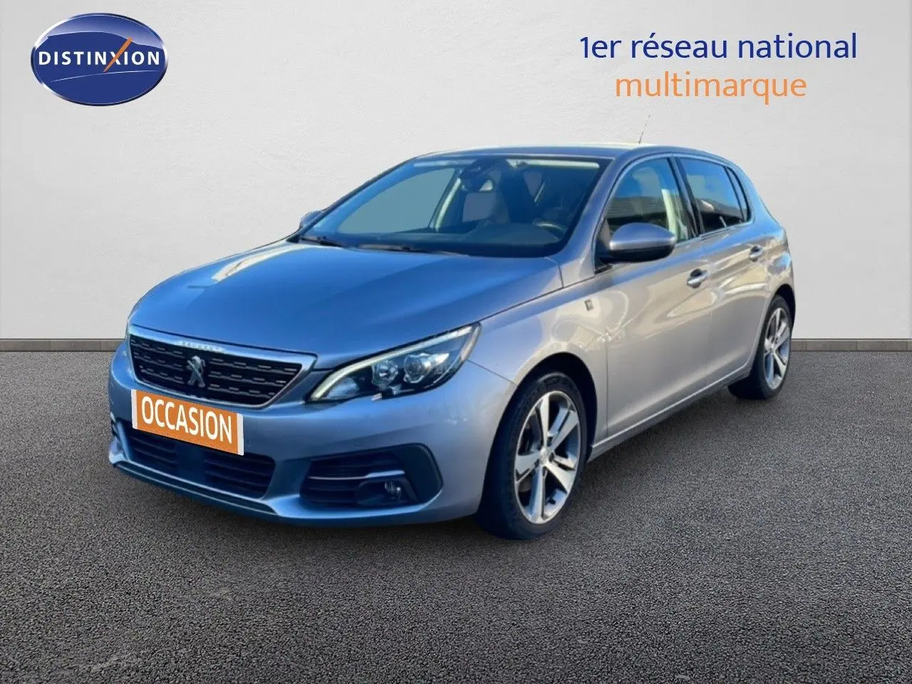Peugeot 308 gris Artense métal vue 3/4 avant droit sur fond neutre avec plaque occasion orange.