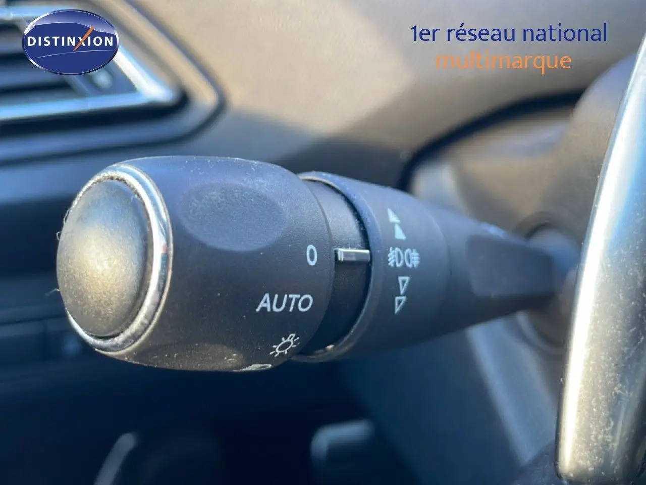Gros plan sur la commande des phares en mode automatique à l'intérieur d'une Peugeot 308 gris Artense de 2019.