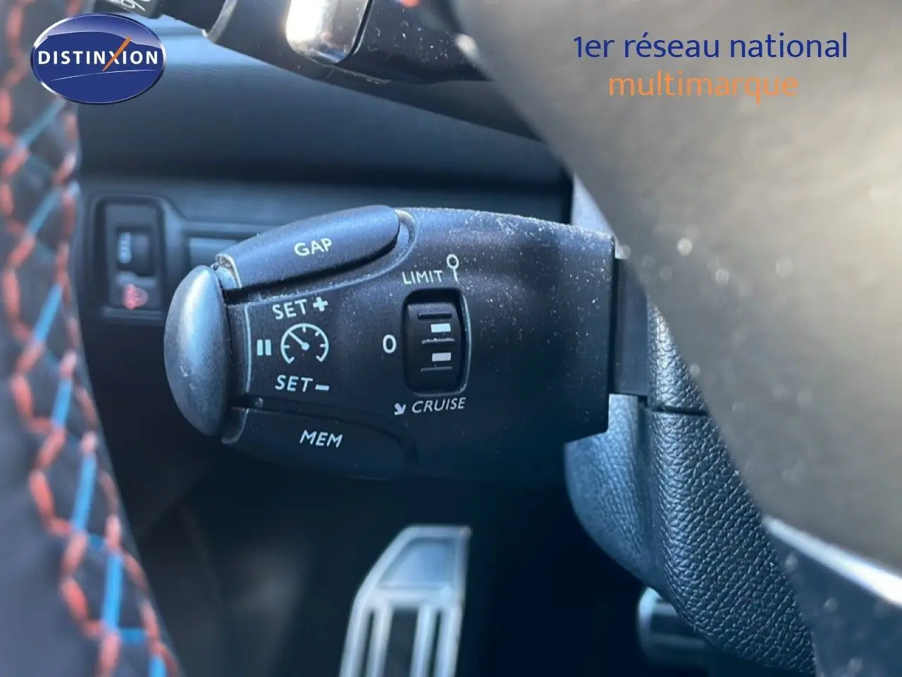Gros plan sur la commande de régulateur de vitesse au volant d’une Peugeot 308 gris Artense, intérieur cuir noir.