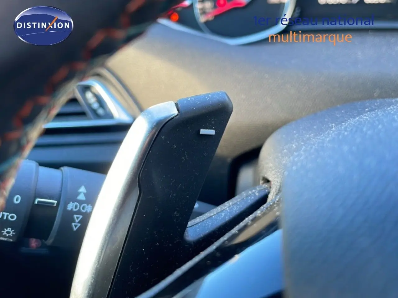 Gros plan sur la palette de changement de vitesse côté droit du volant d’une Peugeot 308 gris Artense, intérieur visible.