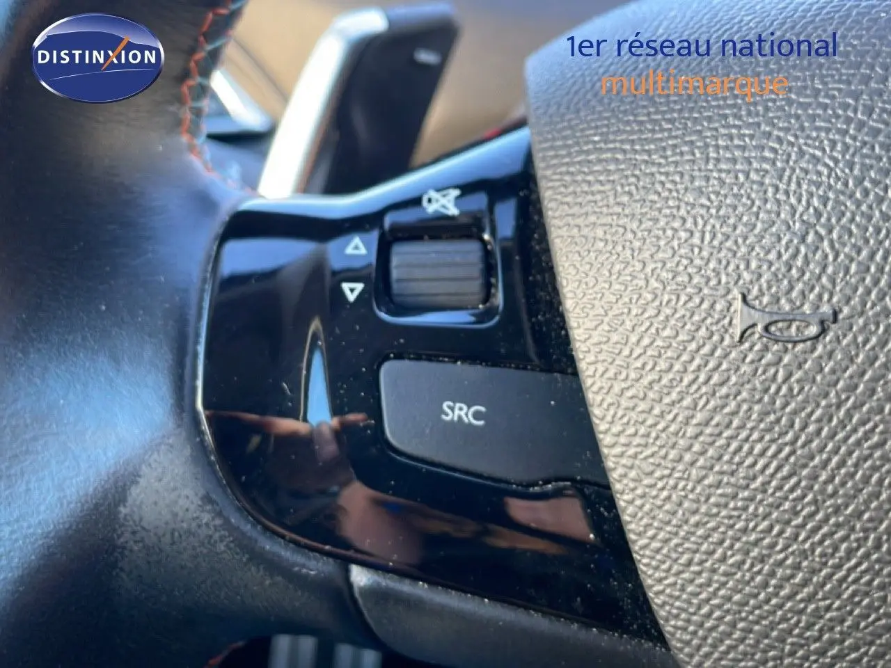 Gros plan sur les commandes noires du volant de la Peugeot 308 gris Artense, mettant en valeur les boutons SRC et volume.