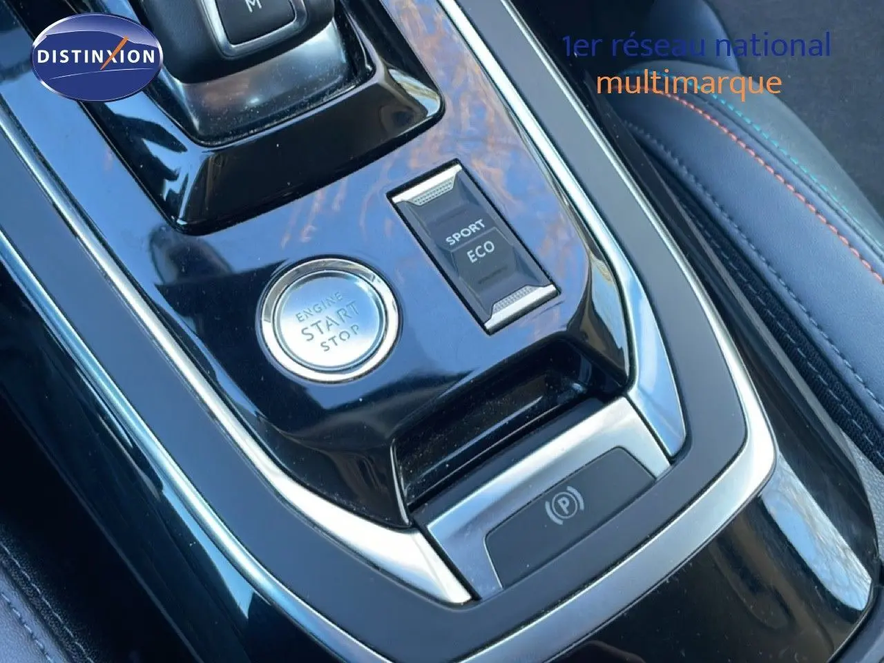 Gros plan sur la console centrale noire brillante de la Peugeot 308 gris Artense, avec bouton start/stop et sélecteur modes sport/eco.
