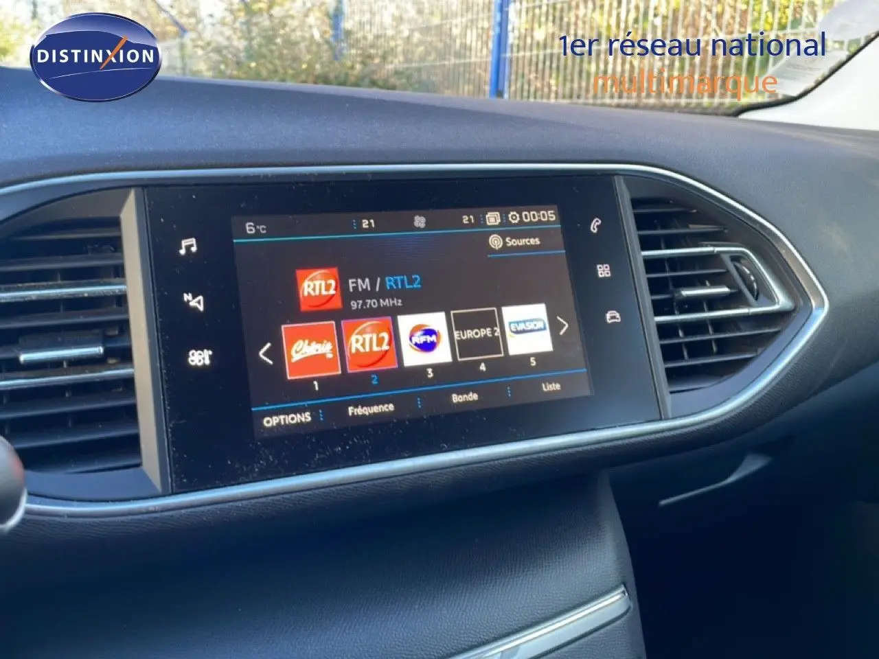 Écran tactile central de la Peugeot 308 gris Artense, affichant les stations radio avec commandes autour et aérateurs latéraux.