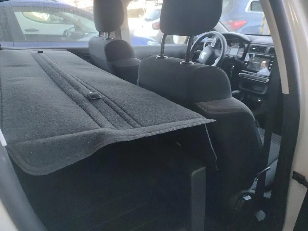 Vue intérieure côté droit d'une Citroën C3 Société blanche, montrant les sièges avant et la tablette arrière déployée.