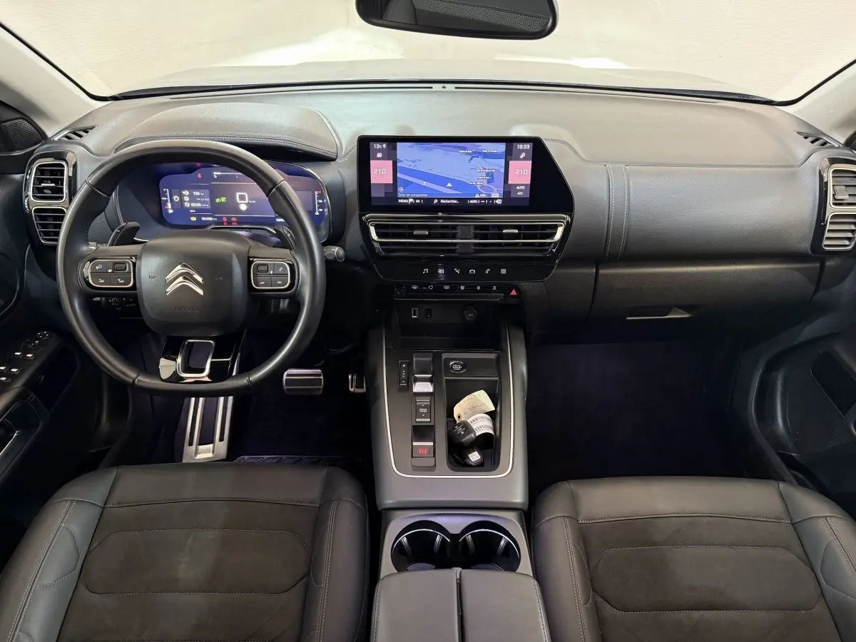 Vue intérieure avant du Citroën C5 Aircross 2023, tableau de bord noir avec écran tactile central et volant cuir multifonctions.