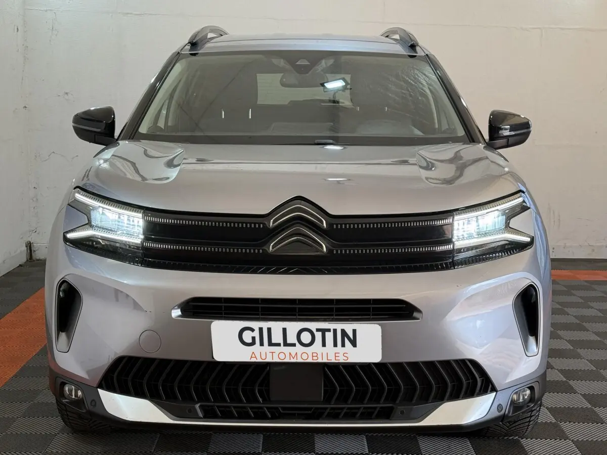 Vue frontale d'un Citroën C5 Aircross gris clair avec phares LED allumés et calandre noire distinctive.