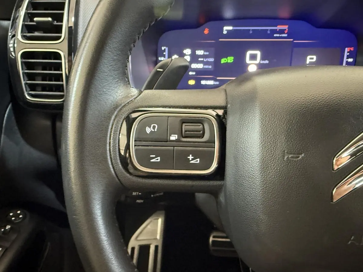 Gros plan sur le volant cuir noir côté gauche du Citroën C5 Aircross 2023 avec commandes intégrées et tableau de bord numérique.