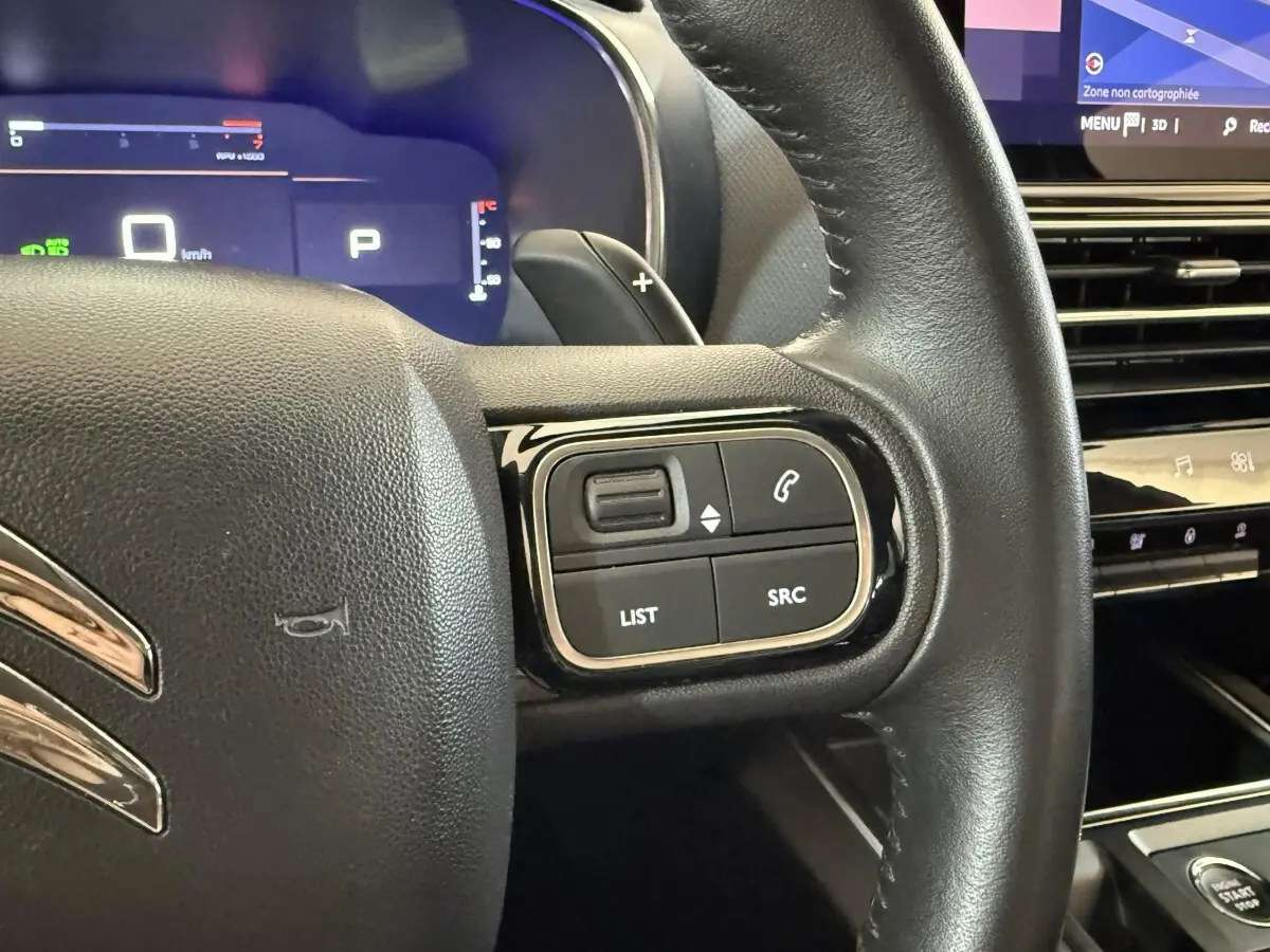Gros plan sur le volant cuir noir côté droit du Citroën C5 Aircross 2023 avec commandes audio et tableau de bord numérique.