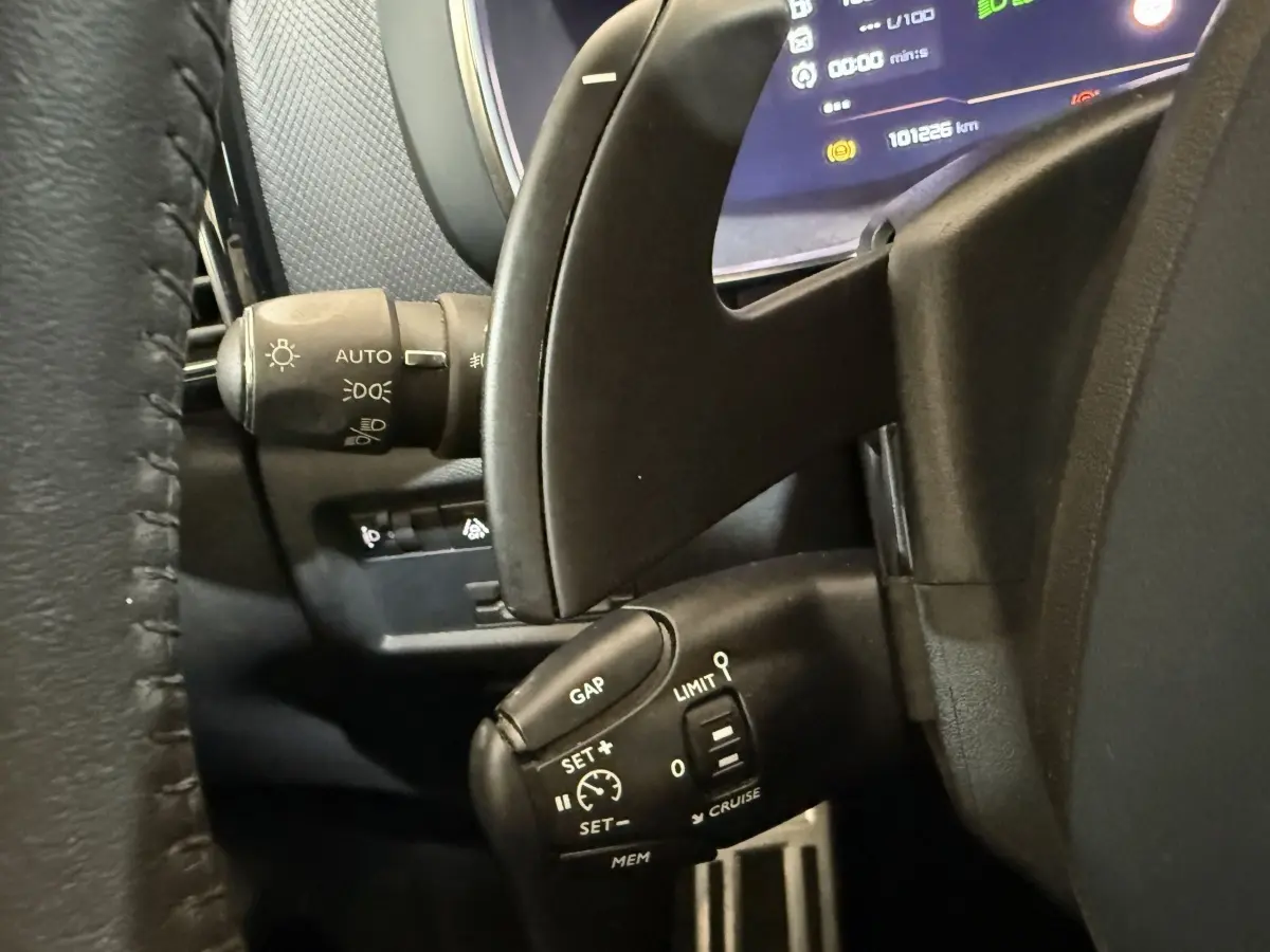 Gros plan sur la commande de régulateur de vitesse et les palettes au volant d’un Citroën C5 Aircross gris clair, intérieur noir.